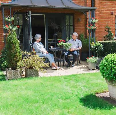 A senior couple enjoying the sun on a green ground floor terrace