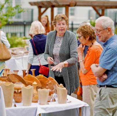 Customers inspect carved wooden items on stall