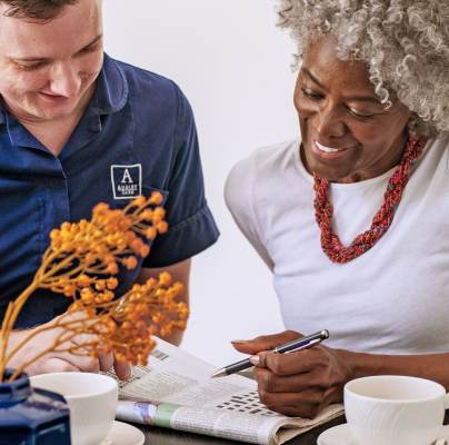 Woman solving crossword with carer