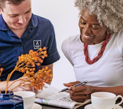 Woman solving crossword with carer