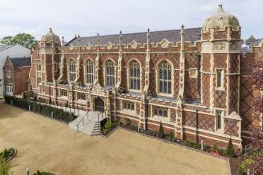 Red-brick mansion with arched windows and stone buttresses