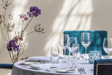 Table setting with purple flowers and plush blue chairs