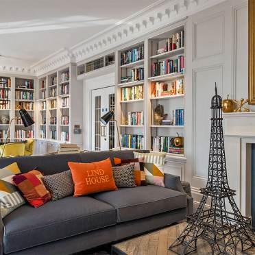 Library interior with an Eiffel tower element on a coffee table and fireplace.