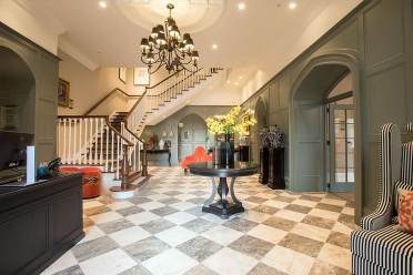 Reception area in Cooper's Hill House, home to the Audley Club Reception area with chess tiles on the floor, chandelier and luxury decor