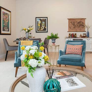 Living room with teal furniture and round glass coffee table