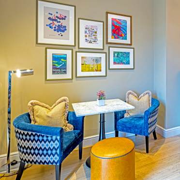 Two blue armchairs with caramel leather stools in the middle