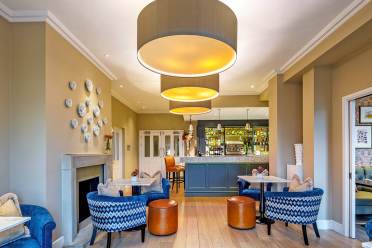 Bistro with blue armchairs, caramel leather stools and beige walls