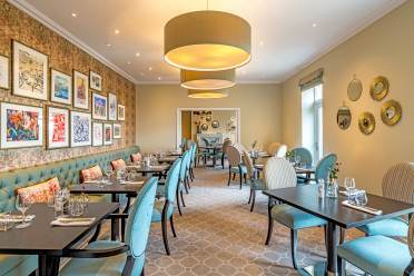 Long room with small tables and light blue chairs