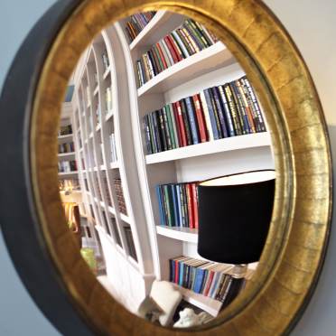 Bookshelves reflected in round wall mirror