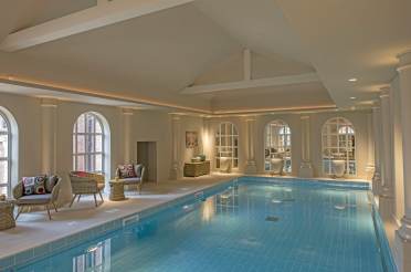 Softly lit blue pool with columns and arched windows