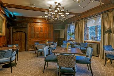 Tudor style restaurant interior with alabaster chairs and 4 seat square tables