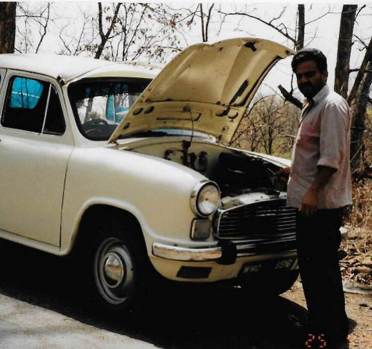 Driver standing by Ambassador car with open bonnet