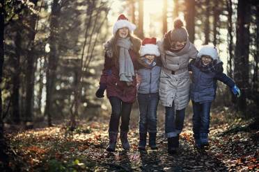A Christmas walk is traditional after a generous festive roast lunch Young family in woods with Christmas hats