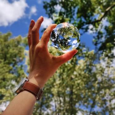 Blue sky through a glass ball in hand