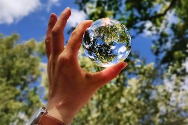 Blue sky through a glass ball in hand