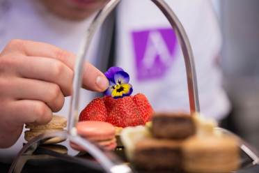 Chef adding edible flower to cakes on stand