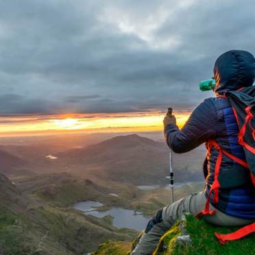 A hiker's watching the scenery and resting on the edge of a hill