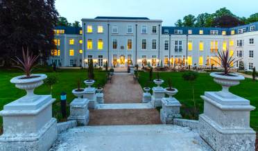 As evening falls, on come the terrace lights at beautiful Inglewood House Looking over stone steps to lit terrace in the evening