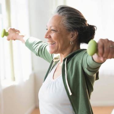 A senior lady lifting small weights, arms on the sides