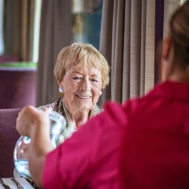 Woman smiles as carer pours water