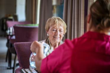 Woman smiles as carer pours water