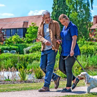 Man and female carer walking dog