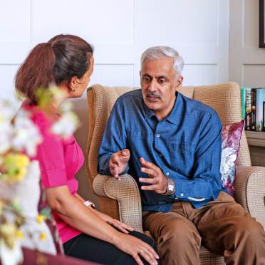 Seated man talking with carer