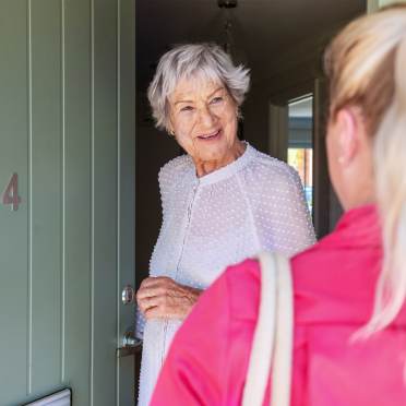 Older woman answering door to carer