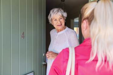 Woman opening front door to carer