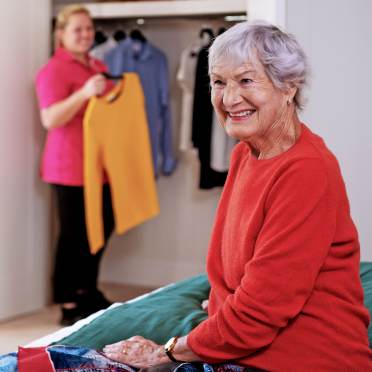 Carer helping elderly women with her outfit