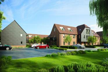A residential complex with brick and wood buildings, a parking area with cars, and green lawns under a clear blue sky.