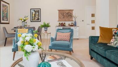 Living room with teal furniture and round glass coffee table