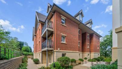 Three-story brick apartment building with balconies and a paved courtyard.