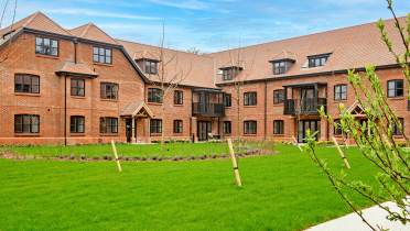 Red brick apartment block with lawn