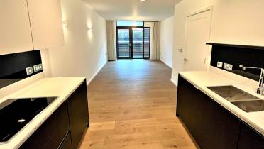 Kitchen leading on to empty living area