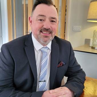 A smiling middle aged man in a suit 