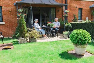 A senior couple enjoying the sun on a green ground floor terrace