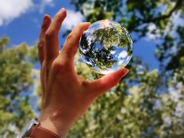 Blue sky through a glass ball in hand