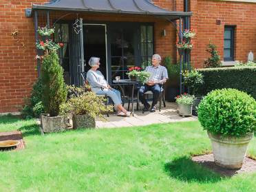A senior couple enjoying the sun on a green ground floor terrace