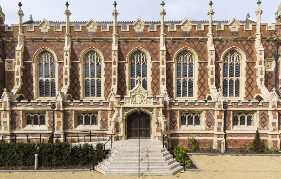 Red-brick mansion with arched windows and stone buttresses