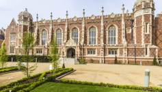 Red-brick mansion with arched windows and stone buttresses