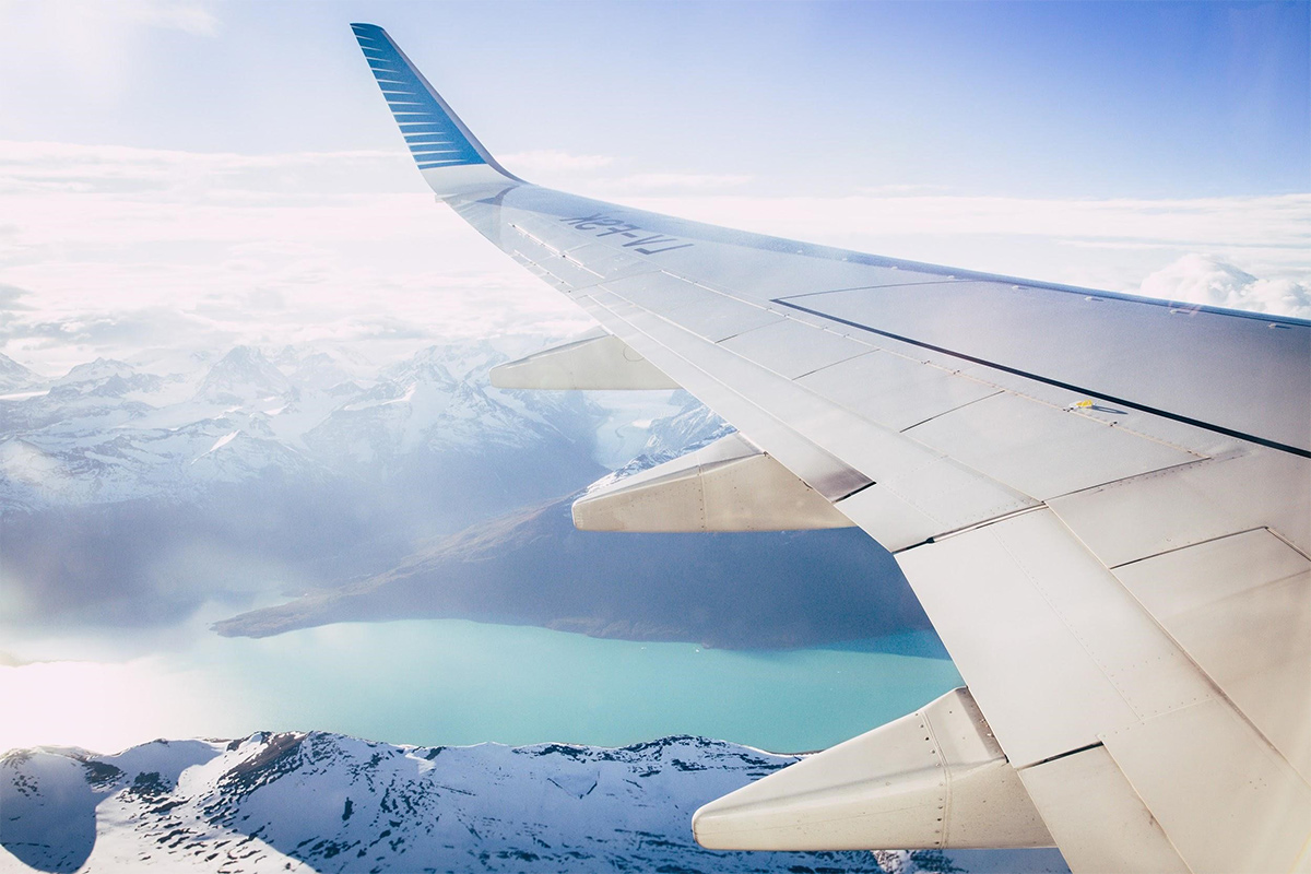 An airplane wing with clouds below